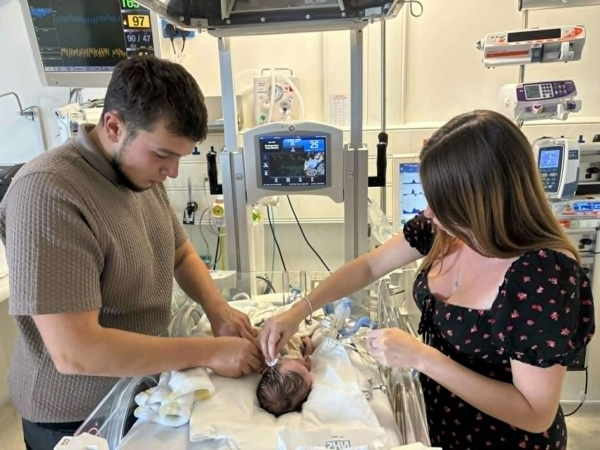Both parents tending to Noah in the incubator